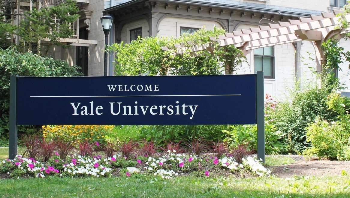 sign at Yale University entrance, featuring the university's name and logo.